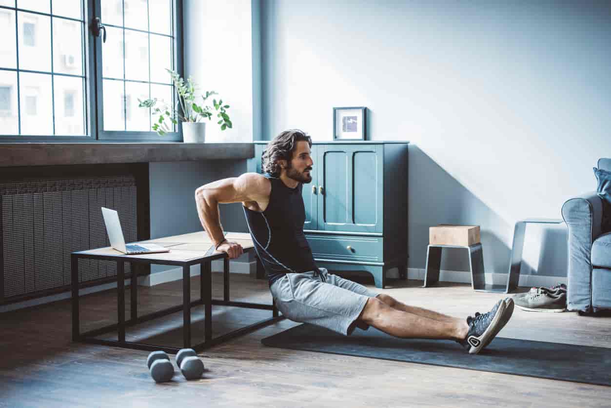 Mann macht Krafttraining zu Hause - Dips im Wohnzimmer ohne Geräte